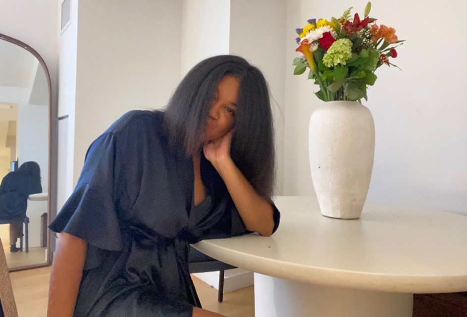 Blogger Zora Voyce sitting at a table with flowers in a vase.