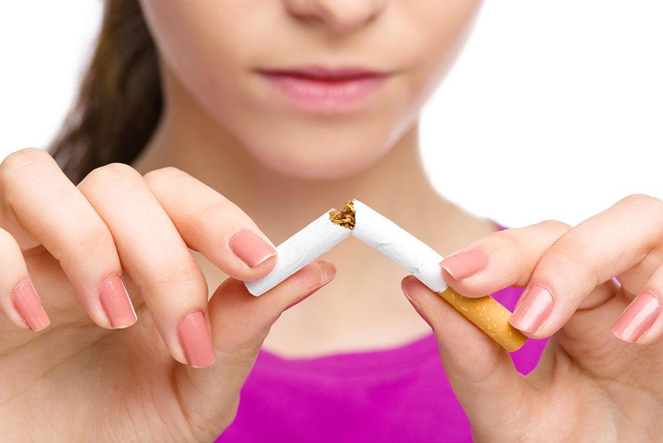 Closeup of woman breaking a cigarette in half.