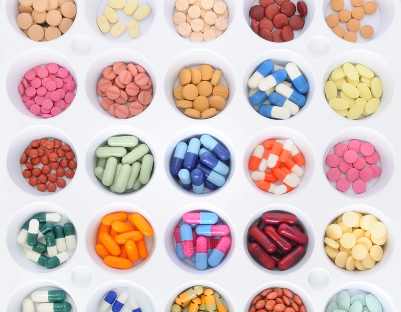 Several bowls of different colored medications in rows.