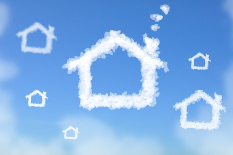 Blue sky with white clouds shaped like houses. 