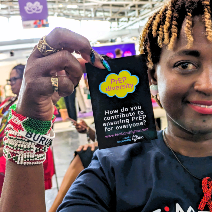 Eliane (HIVstigmafighter) holding up a badge that reads &quot;PrEP diversity&quot;.