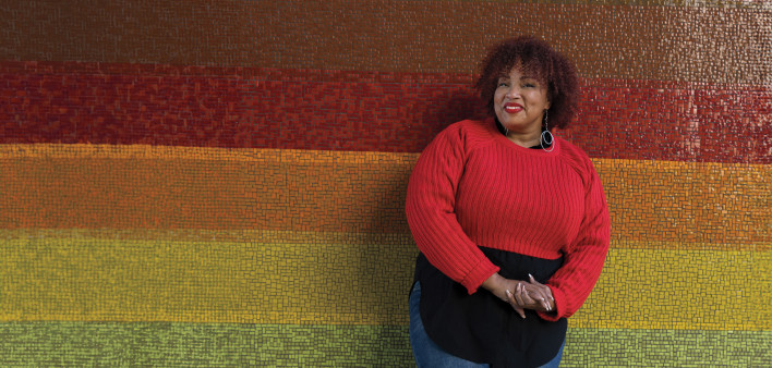 Bridgette Picou standing in front of a colorful mosaic wall.