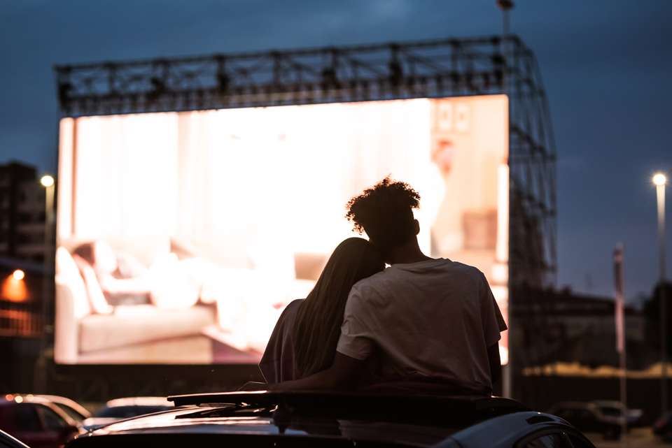 Silhouette of the backs of two people watching an outdoor movie.