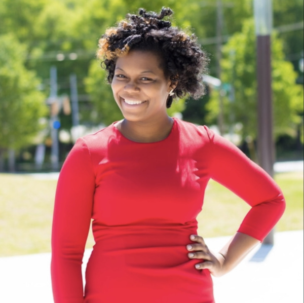 Masonia Traylor, smiling, standing outside in a red dress.