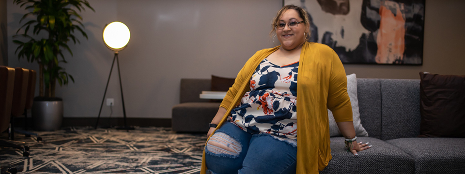 Marissa Gonzalez, sitting on a sofa, smiling.