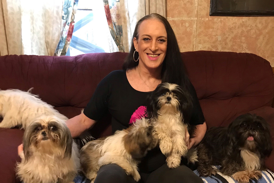 Katie Willingham, smiling, sitting on sofa with five small dogs.