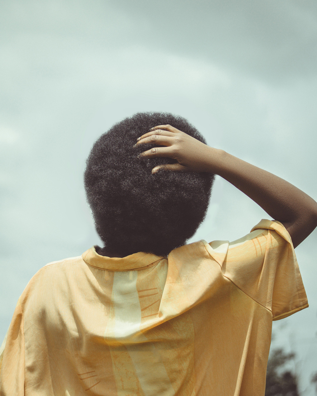 Back view of a woman with her hand on the back of her head.