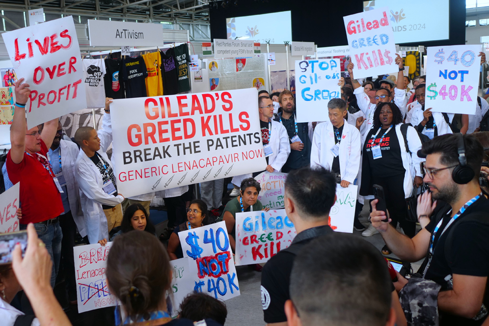 Group of people holding signs saying &quot;Lives over profit&quot; and other slogans.