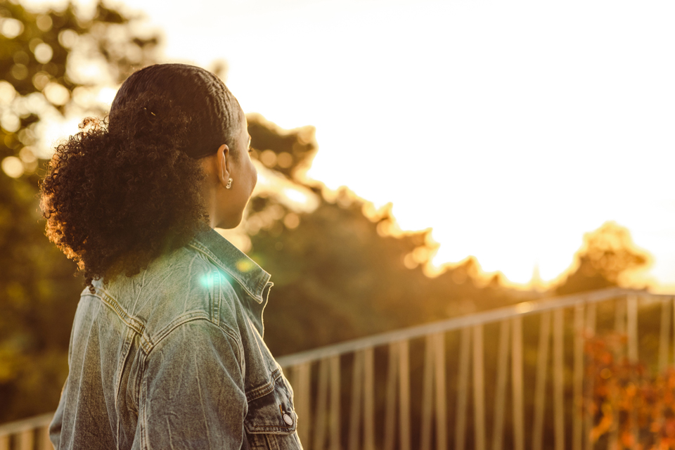 Mujer mirando una vista de árboles y un hermoso cielo.