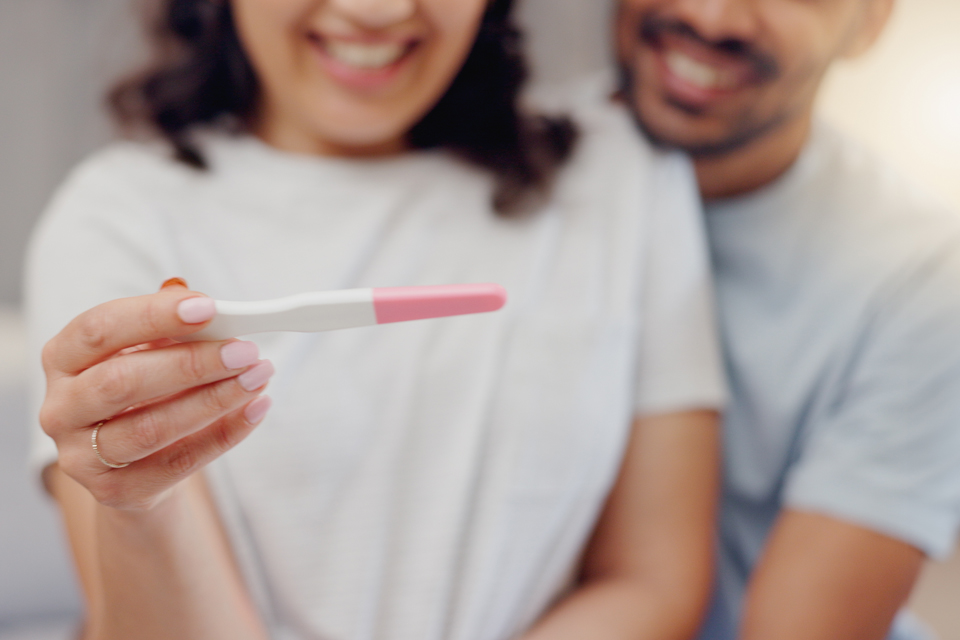 A couple, smiling, looking at the results of a home pregnancy test.