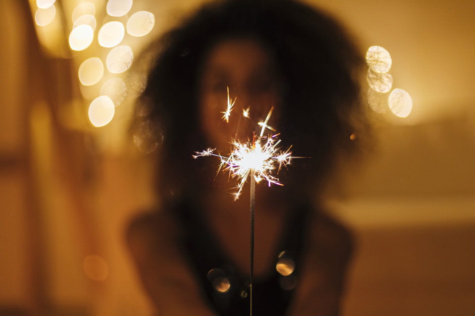 Woman holding a sparkler in front of her.