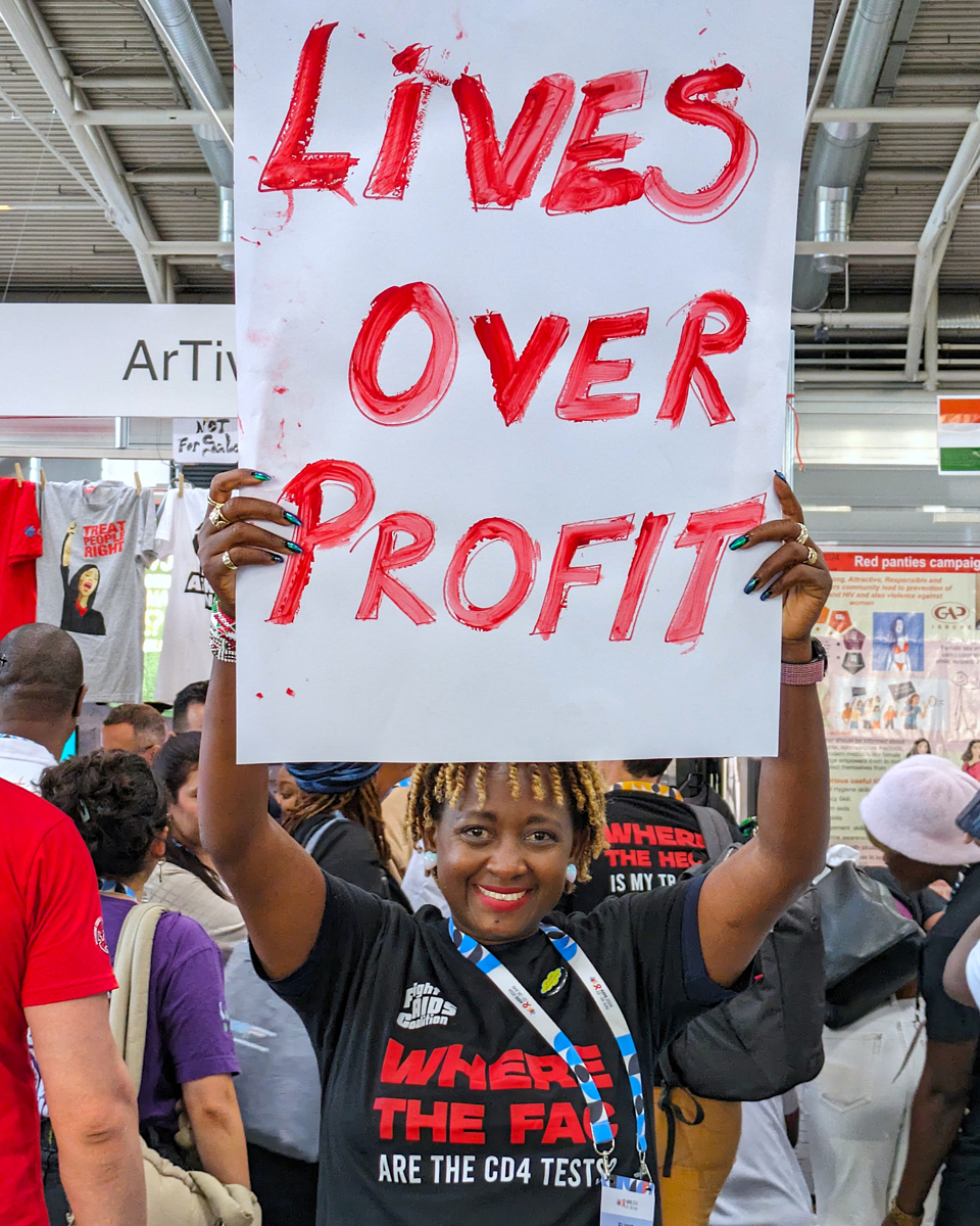 A Girl Like Me blogger Eliane (HIVstigmafighter) holding a sign that says &quot;Lives over profit&quot;.