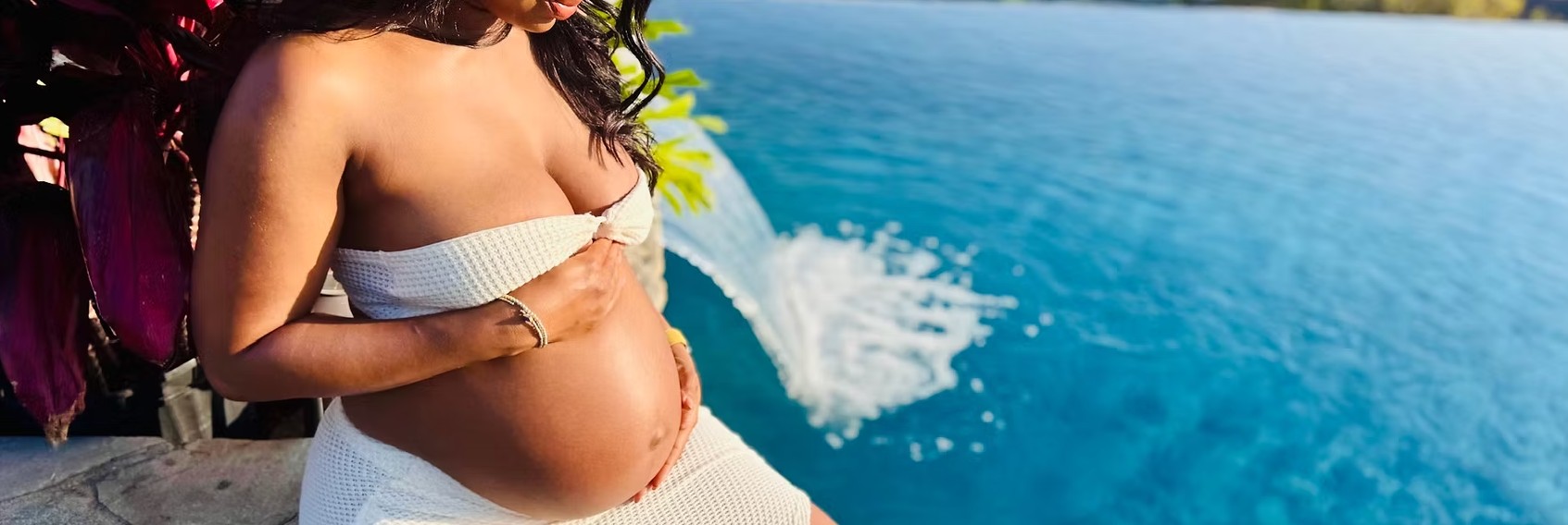 A pregnant woman next to water.