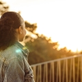 Woman looking at a view of trees and a beautiful sky.