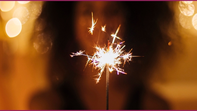 Woman holding a sparkler in front of her.