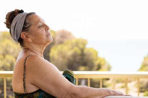 Mujer con los ojos cerrados y de cara al sol.