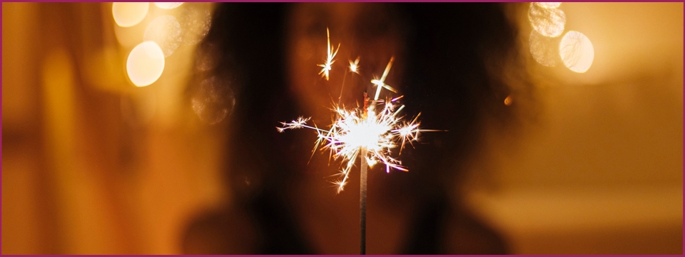 Woman holding a sparkler in front of her.