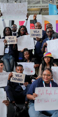 Group of people holding signs saying &quot;Visa denied&quot;.